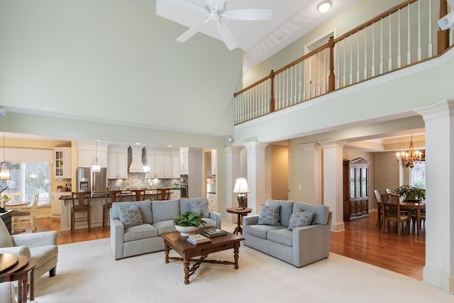 living room with a towering ceiling, plenty of natural light, and light wood-style floors