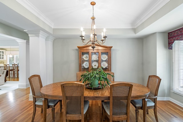 dining space with an inviting chandelier, crown molding, light wood-style floors, baseboards, and a tray ceiling