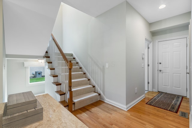 entryway with stairway, baseboards, light wood-style flooring, and visible vents