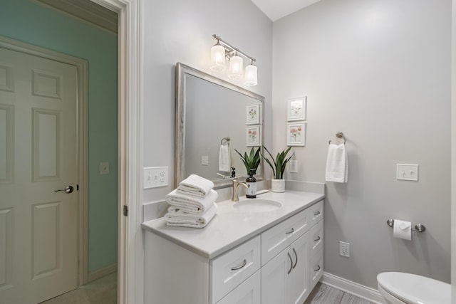bathroom with vanity, baseboards, and toilet