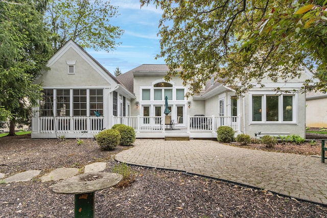 back of house with a wooden deck, stucco siding, a sunroom, and a patio area