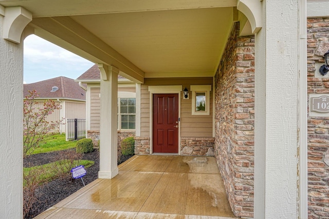 property entrance featuring a porch, stone siding, and brick siding