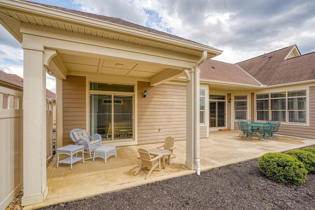 rear view of house with roof with shingles and a patio area