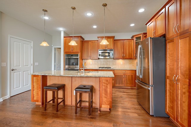 kitchen with a sink, appliances with stainless steel finishes, tasteful backsplash, and brown cabinetry
