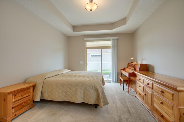 bedroom featuring access to outside, light carpet, and a raised ceiling