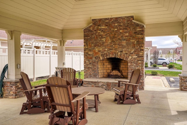 view of patio with fence, outdoor dining space, and an outdoor brick fireplace