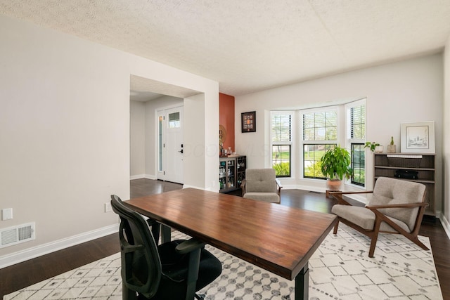dining area featuring baseboards, wood finished floors, visible vents, and a textured ceiling