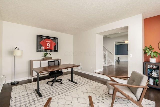home office featuring baseboards, wood finished floors, and a textured ceiling