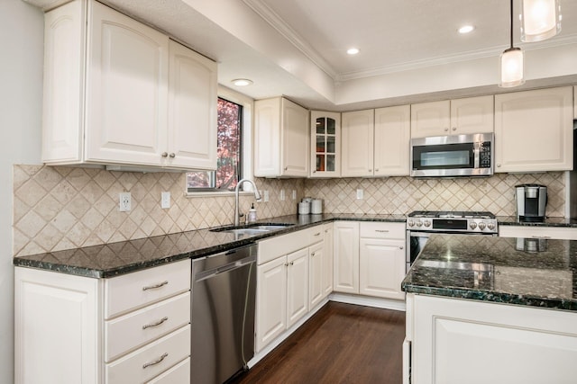 kitchen featuring dark wood finished floors, a sink, crown molding, dark stone counters, and appliances with stainless steel finishes