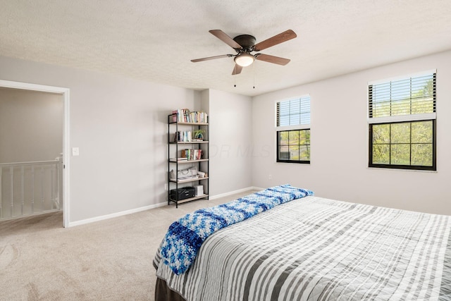 carpeted bedroom featuring a ceiling fan, baseboards, and a textured ceiling