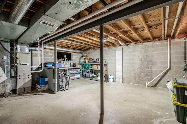unfinished basement featuring concrete block wall and visible vents