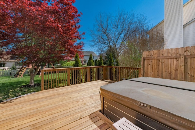 wooden deck featuring a lawn, a hot tub, and fence