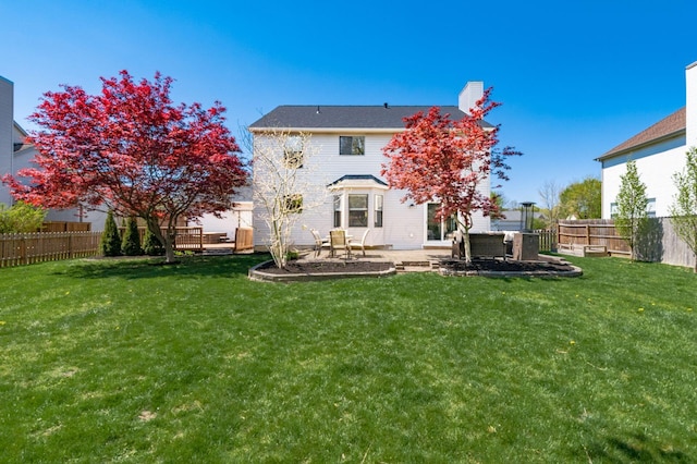 rear view of house with a patio area, a fenced backyard, and a yard
