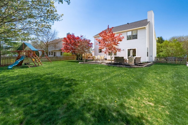 rear view of property featuring a chimney, a fenced backyard, and a lawn