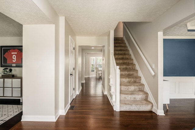 stairs with baseboards, wood finished floors, and a textured ceiling