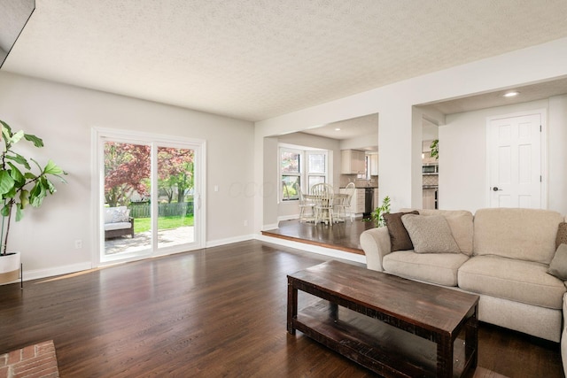 living area with recessed lighting, dark wood finished floors, a textured ceiling, and baseboards