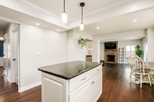 kitchen featuring crown molding, baseboards, white cabinetry, a brick fireplace, and dark wood-type flooring