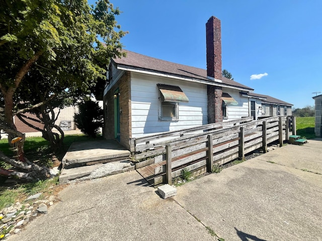 view of front of property featuring a chimney and fence