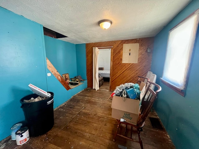 hallway featuring electric panel, wooden walls, a textured ceiling, and hardwood / wood-style flooring