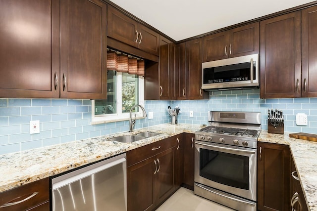 144 Serran Dr, Gahanna, OH 43230 - kitchen featuring stainless steel appliances, a sink, dark brown cabinets, decorative backsplash, and light stone countertops