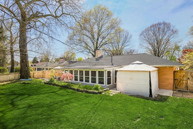 144 Serran Dr, Gahanna, OH 43230 - back of property featuring a fenced backyard, a gate, a chimney, a lawn, and a sunroom