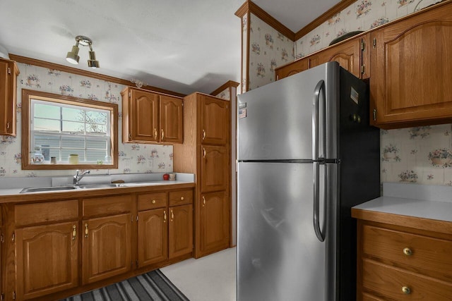 230 Norman Ln, Reynoldsburg, OH 43068 - kitchen featuring brown cabinets, wallpapered walls, ornamental molding, a sink, and freestanding refrigerator