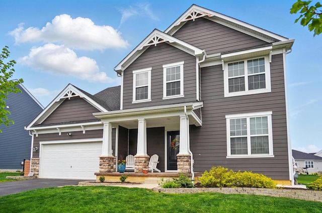 craftsman inspired home featuring aphalt driveway, stone siding, covered porch, a front yard, and a garage