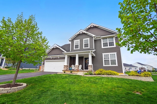 craftsman-style home with a garage, a porch, aphalt driveway, and a front lawn