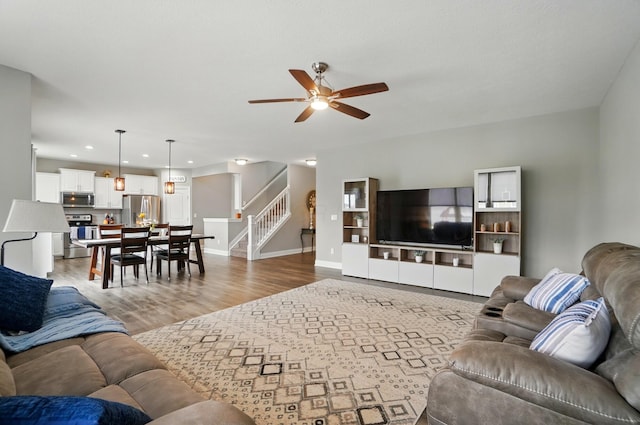 living room with recessed lighting, light wood-style floors, stairs, a ceiling fan, and baseboards