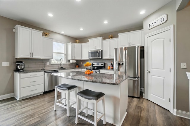 kitchen with a sink, a kitchen island, stainless steel appliances, and tasteful backsplash