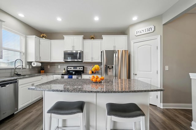 kitchen with dark wood-style floors, stainless steel appliances, backsplash, and a sink