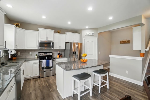 kitchen with white cabinetry, a sink, appliances with stainless steel finishes, and a kitchen island