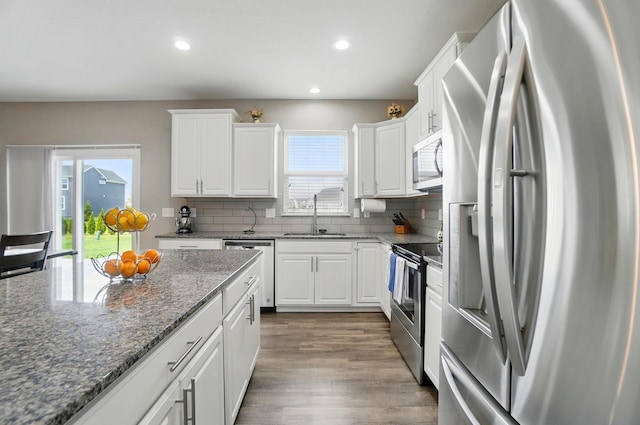 kitchen featuring white cabinets, a sink, stainless steel appliances, recessed lighting, and backsplash