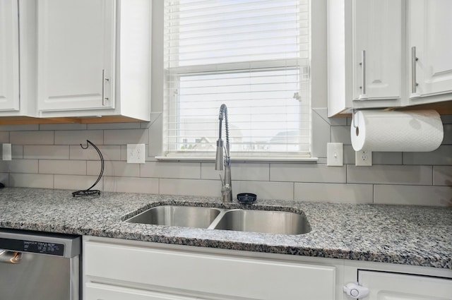 kitchen with tasteful backsplash, stainless steel dishwasher, a wealth of natural light, a sink, and white cabinetry