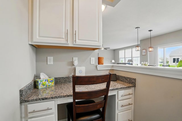 kitchen featuring built in desk, hanging light fixtures, and white cabinets