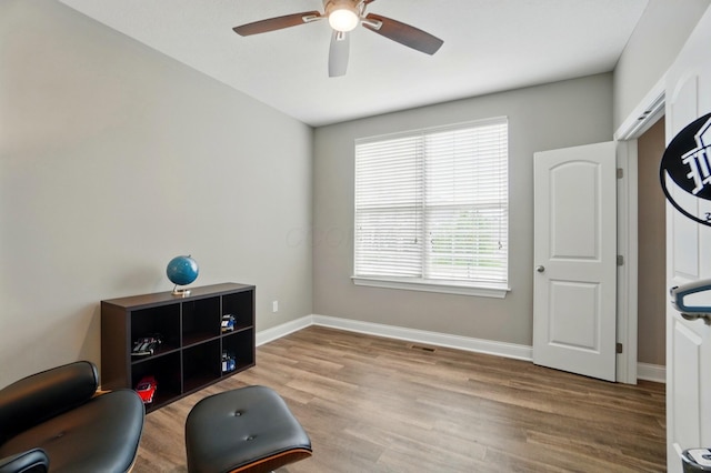 living area with a ceiling fan, visible vents, wood finished floors, and baseboards