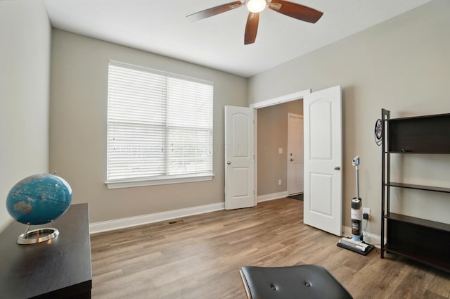 workout area with a ceiling fan, visible vents, light wood-style flooring, and baseboards