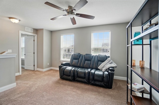 living room featuring visible vents, a ceiling fan, baseboards, and carpet floors