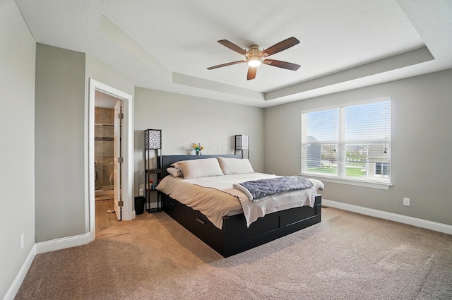 carpeted bedroom featuring baseboards, a ceiling fan, and a tray ceiling