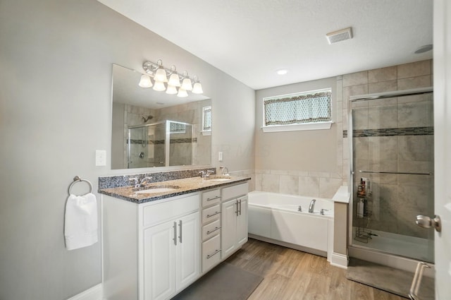 bathroom featuring a sink, visible vents, a garden tub, a stall shower, and wood finished floors
