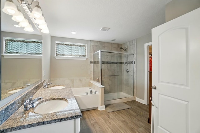 bathroom featuring a garden tub, a sink, a shower stall, and wood finished floors