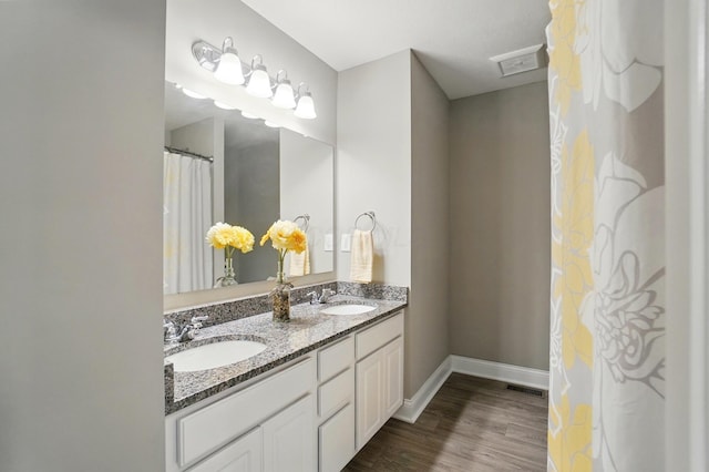full bath featuring baseboards, visible vents, wood finished floors, and a sink