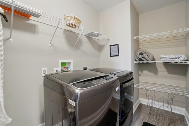 laundry room with washing machine and clothes dryer, wood finished floors, laundry area, and baseboards
