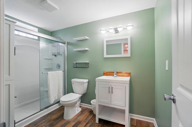 full bathroom with a shower stall, baseboards, toilet, wood finished floors, and vanity