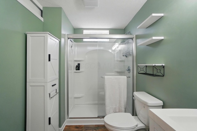 bathroom featuring toilet, a shower stall, wood finished floors, and vanity