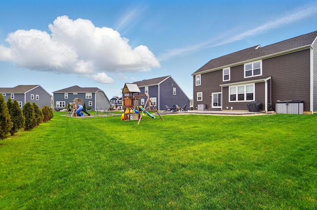 rear view of property featuring a residential view, a lawn, a playground, and a patio area