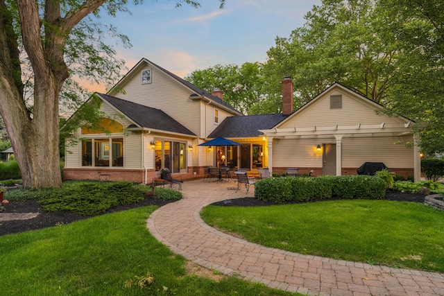 4318 Lyon Dr, Upper Arlington, OH 43220 - back of house at dusk with a pergola, a lawn, a chimney, and a patio