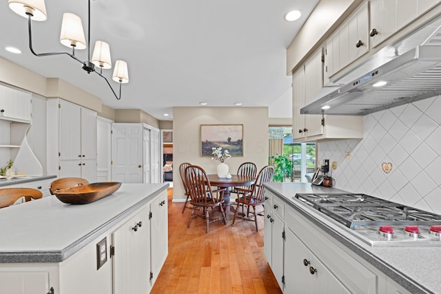 4318 Lyon Dr, Upper Arlington, OH 43220 - kitchen featuring under cabinet range hood, stainless steel gas cooktop, light wood finished floors, decorative backsplash, and white cabinets