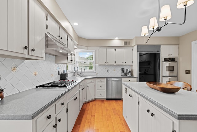 4318 Lyon Dr, Upper Arlington, OH 43220 - kitchen featuring stainless steel appliances, under cabinet range hood, white cabinets, decorative backsplash, and a center island
