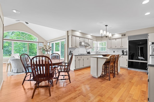 4318 Lyon Dr, Upper Arlington, OH 43220 - kitchen with refrigerator, under cabinet range hood, a chandelier, a center island, and light wood-style flooring